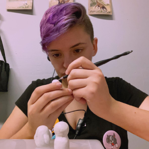 Photo of Savannah Rayne carefully sculpting a small clay creation.